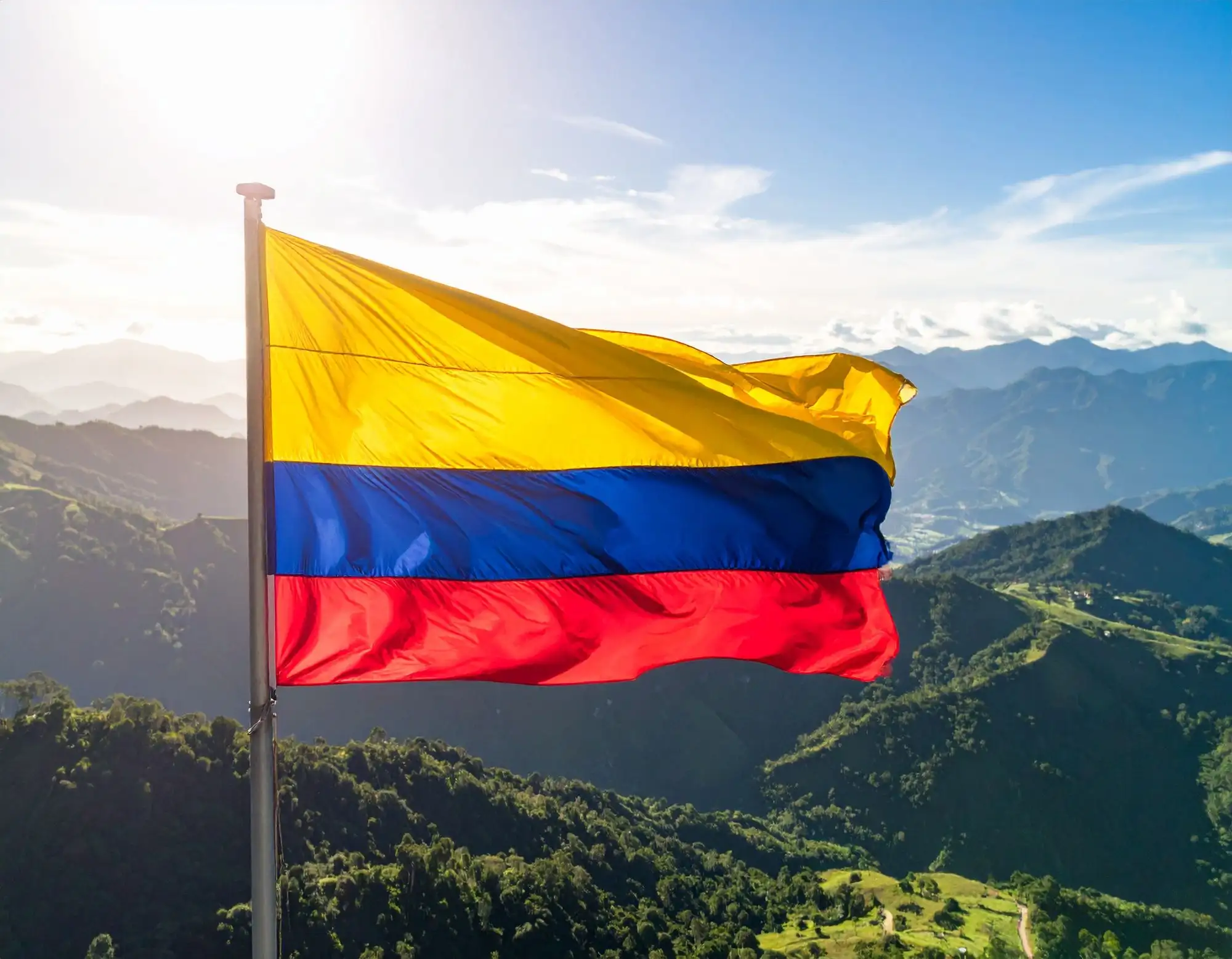 The yellow, blue and red flag of Colombia flying in front of the Andes mountains