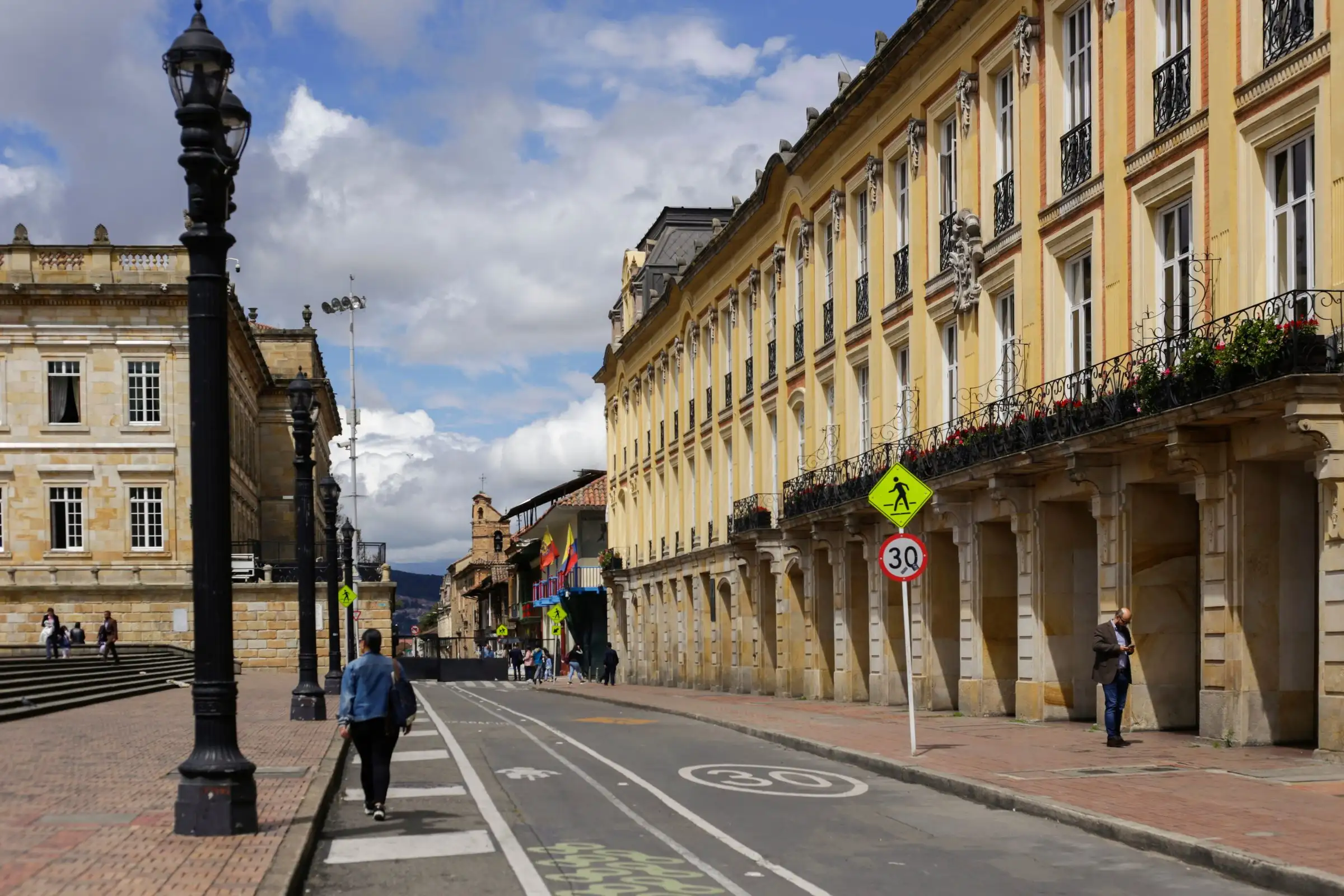 Una calle del centro histórico de Bogotá con edificios neoclásicos y coloniales bajo un cielo con nubes