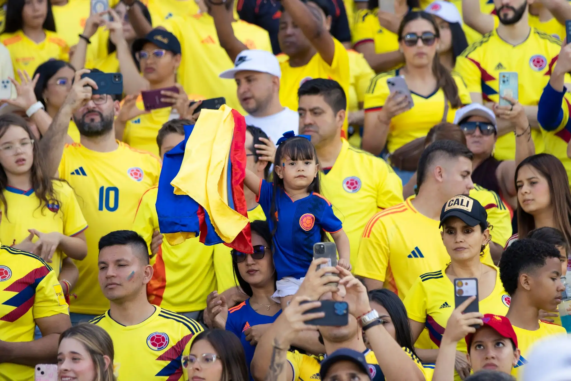 Colombia national football team fans in yellow shirts waving the Colombian flag in a stadium