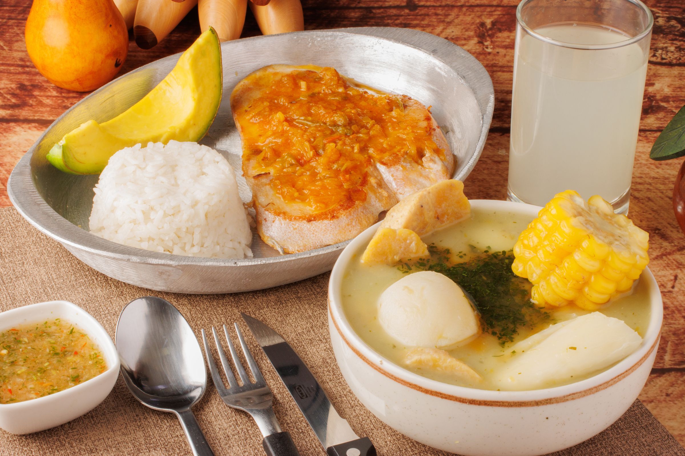 A typical Colombian lunch: sancocho with corn on the cob, cassava and plantain, white rice, avocado, ají sauce and a glass of juice