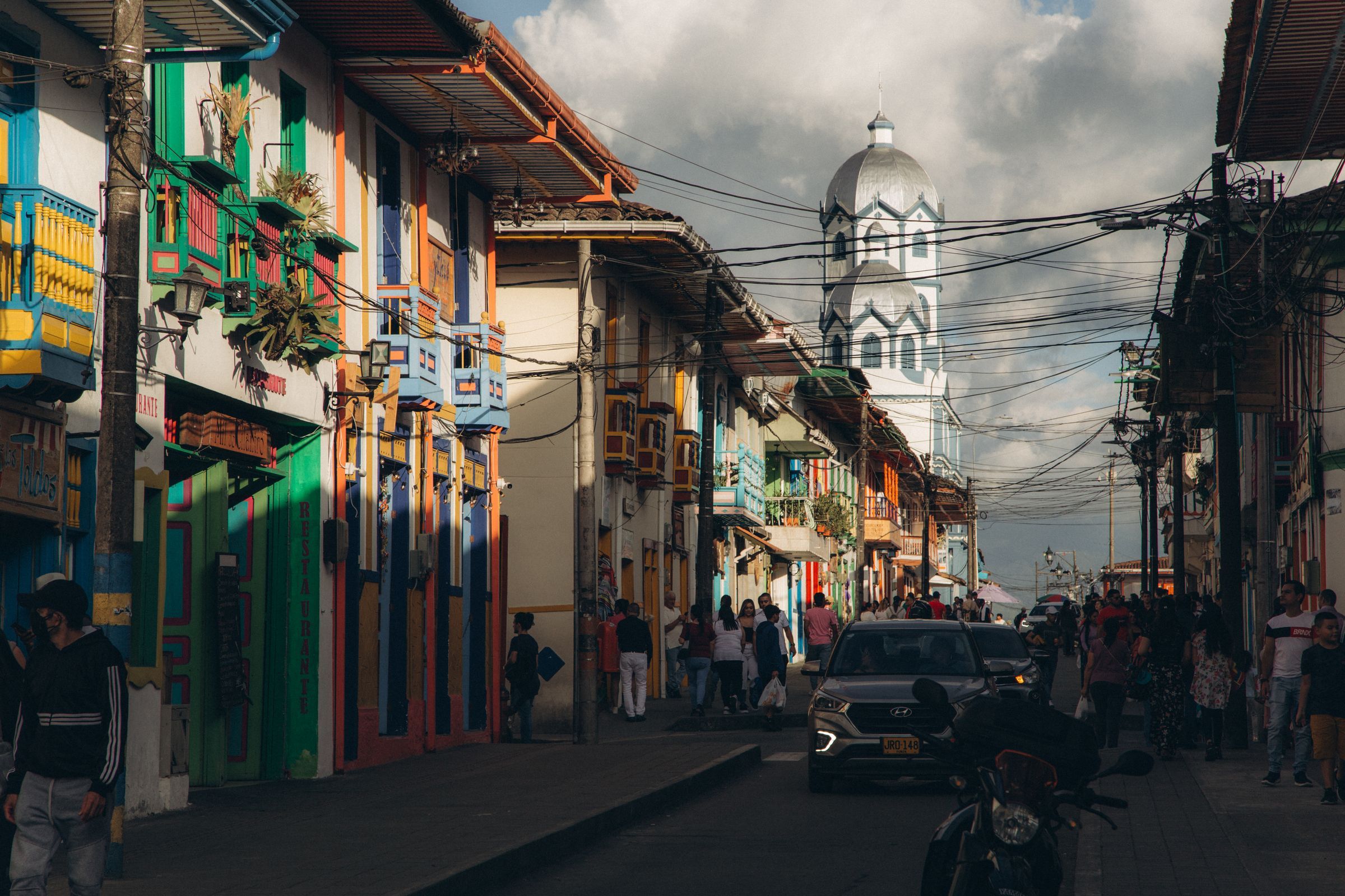 Una calle de Filandia con casas de colores y balcones de madera, con el campanario de la iglesia María Inmaculada al fondo