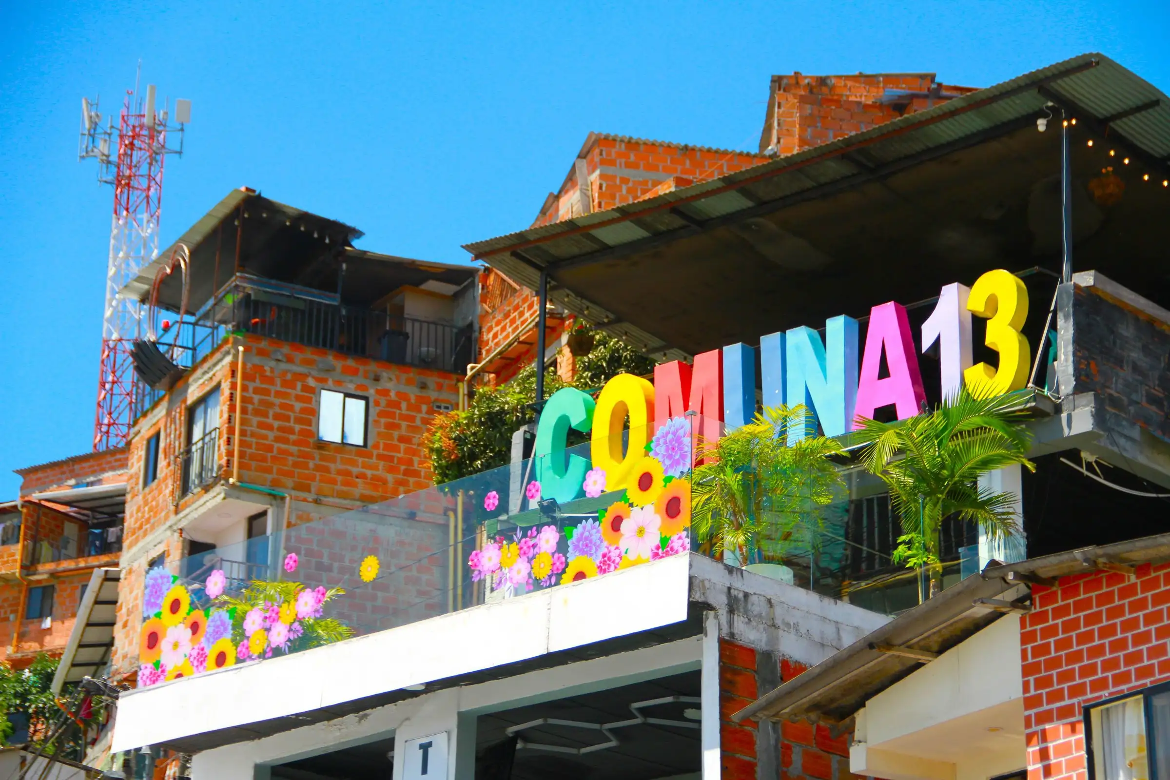 La scritta colorata Comuna 13 sopra le case di mattoni del quartiere, a Medellín