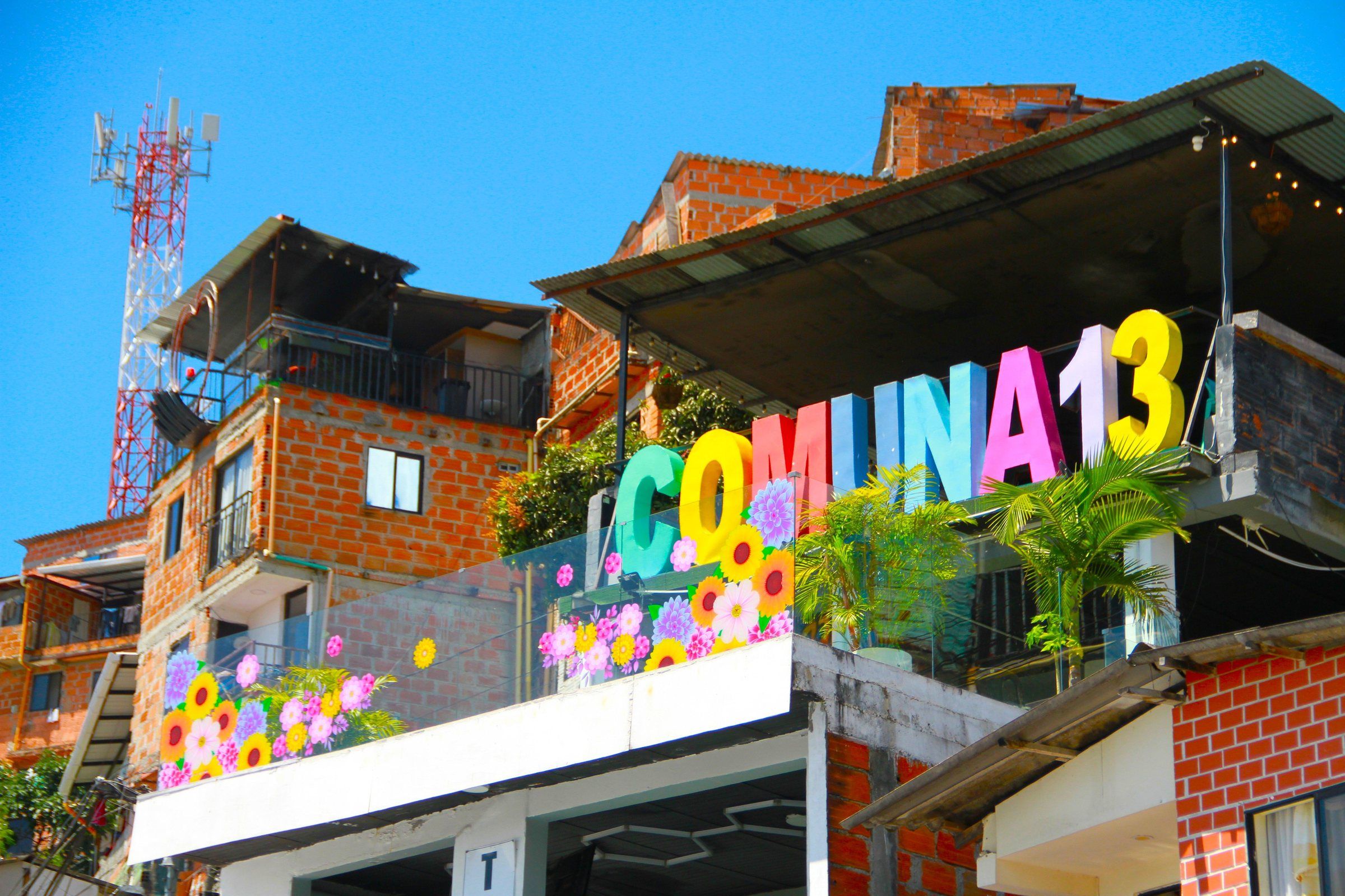 The colourful Comuna 13 sign above the neighbourhood's brick houses in Medellín
