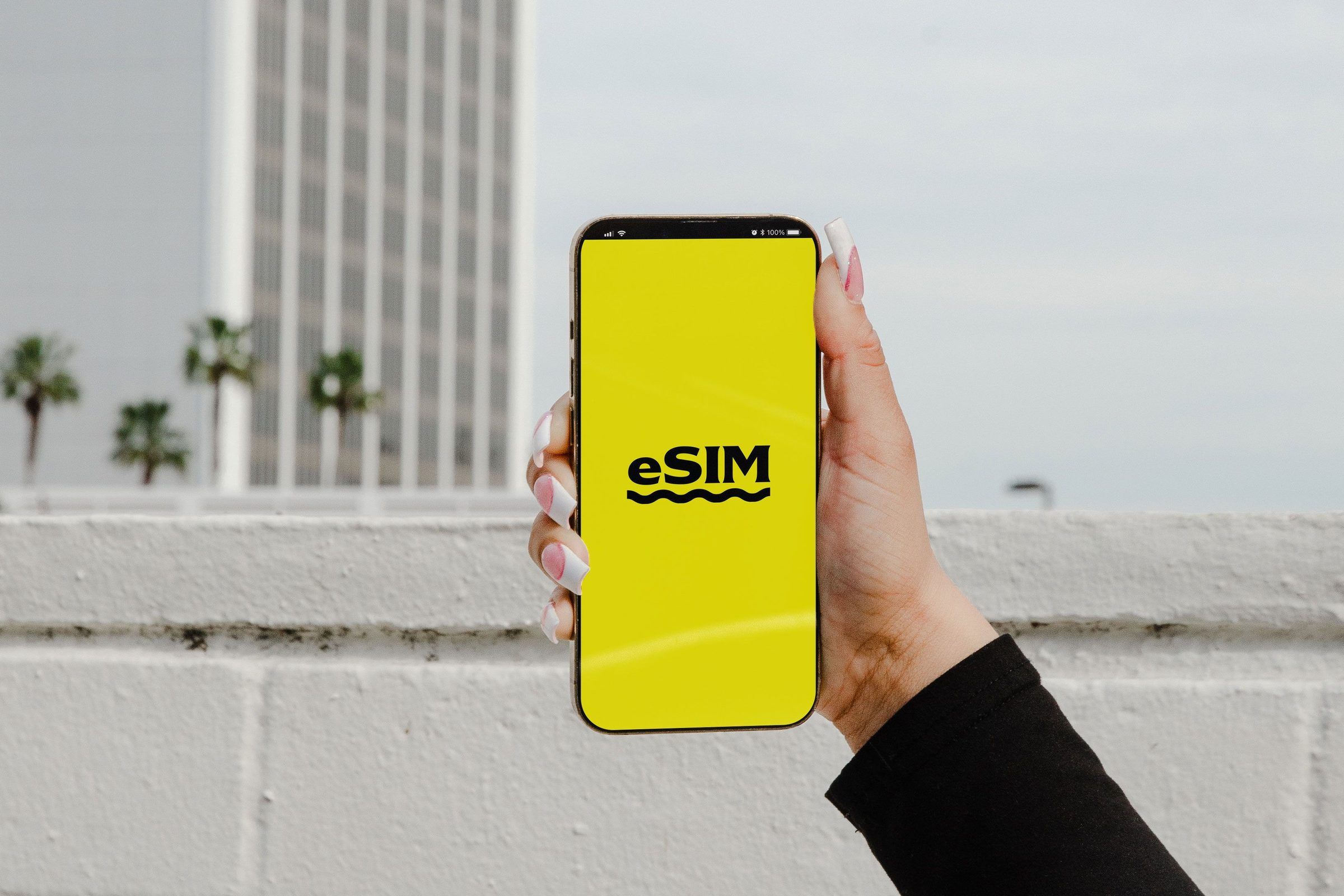 A hand holding a smartphone with the word eSIM on a yellow screen