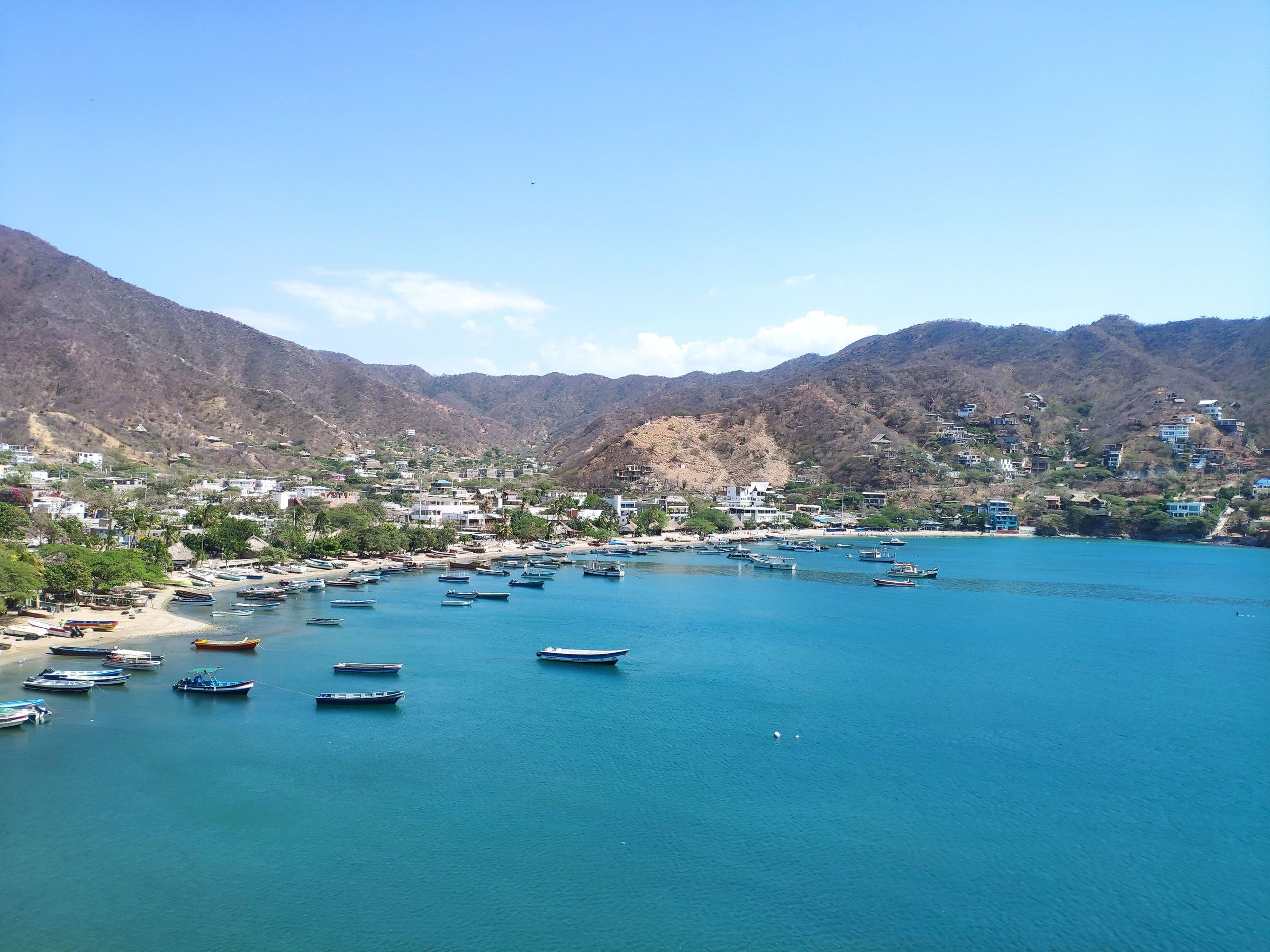 Aerial view of Taganga bay with fishing boats on the turquoise sea and dry hills all around